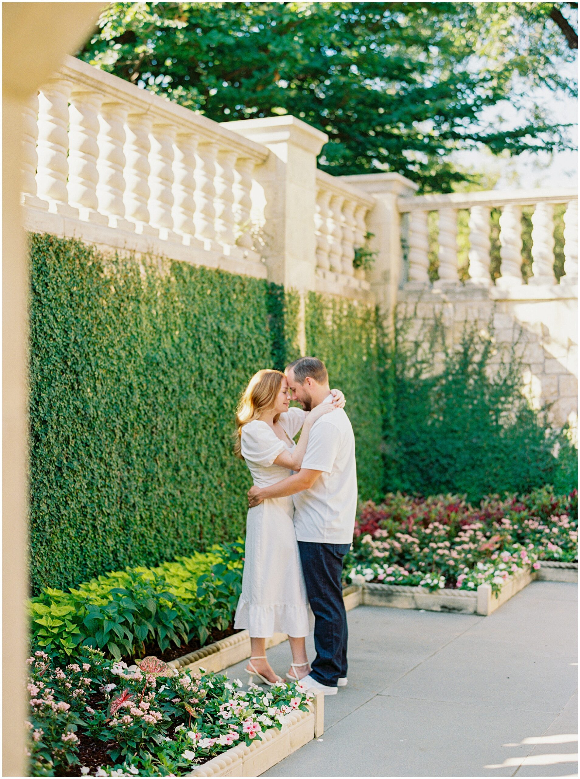 Romantic moment of Corey and Caitlyn standing amidst vibrant blooms in the Poetry Garden.