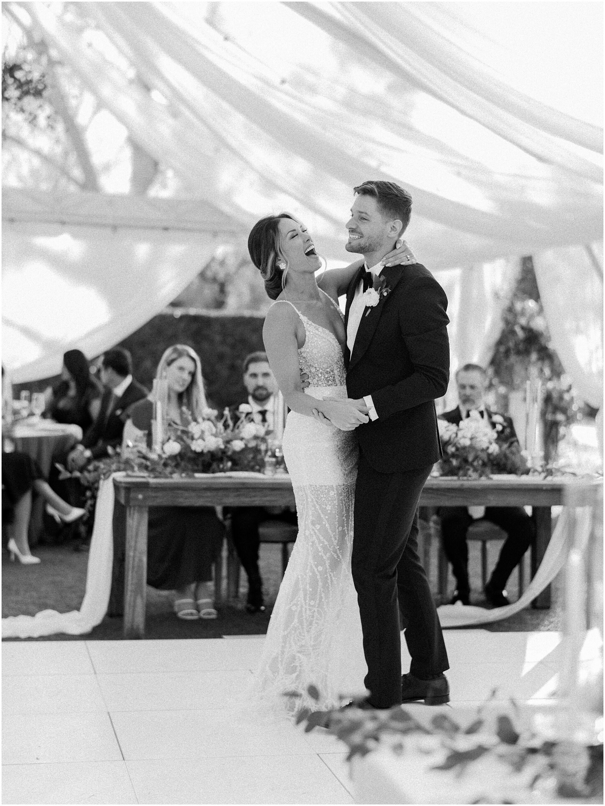 a Candid moment between husband and wife dancing at their wedding reception in black and white